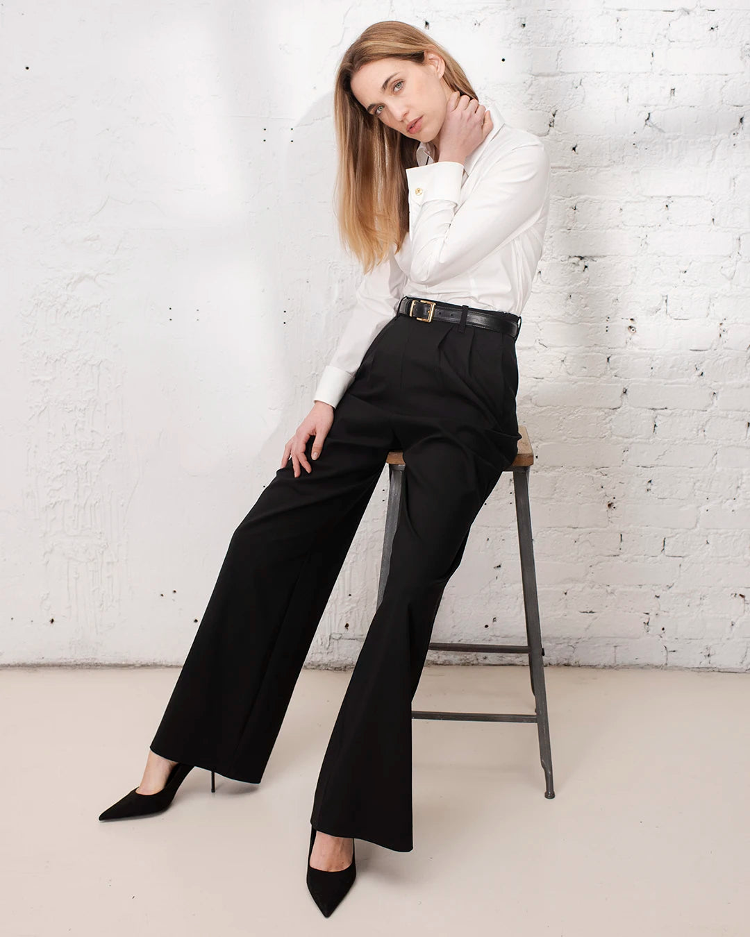 Look professionnel femme avec chemise blanche ajustée, boutons de manchette et pantalon large noir.