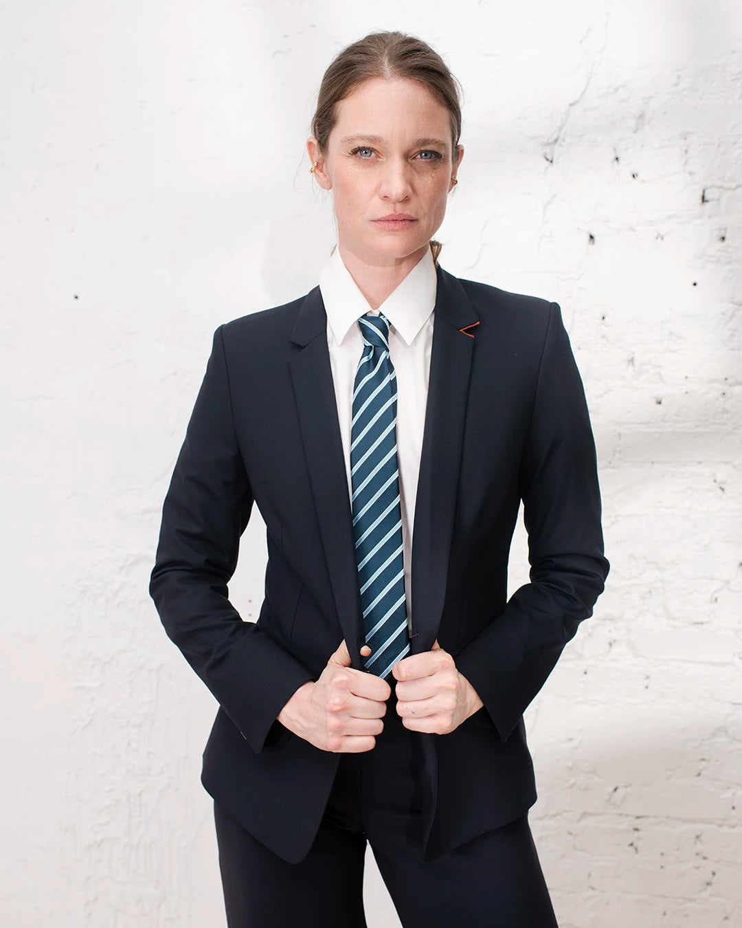 Tenue professionnelle femme avec tailleur bleu marine, veste cintrée et pantalon large structuré.