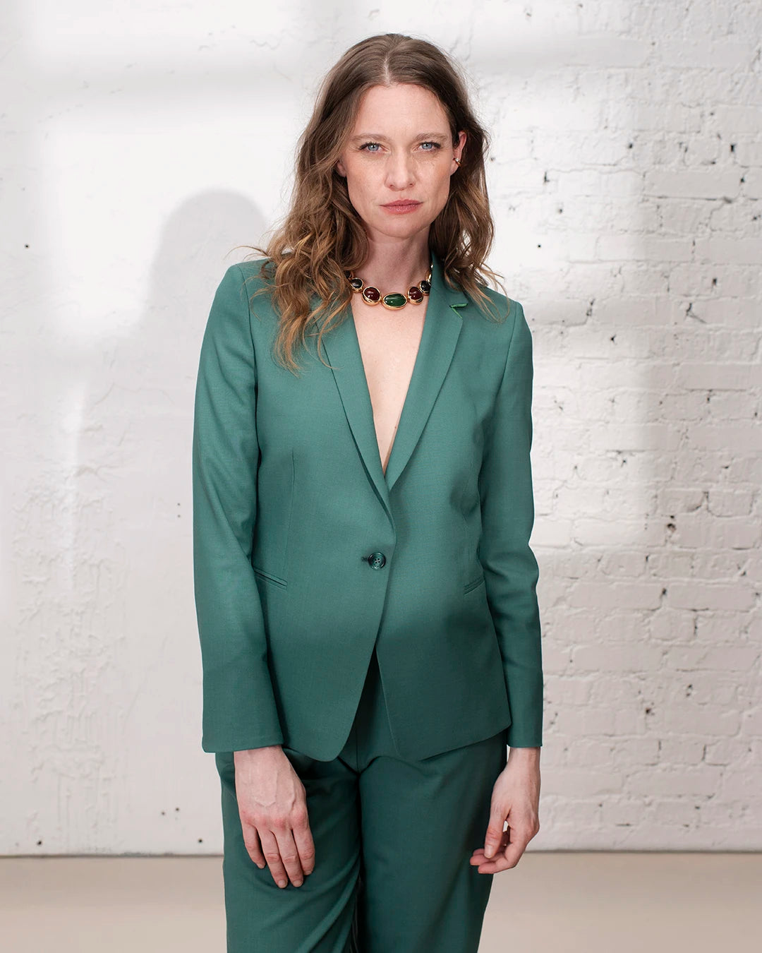Tenue cérémonie femme avec tailleur vert, veste cintrée et pantalon large élégant.